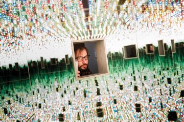 A man looking through a small window at many things
