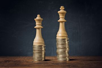 King and Queen chess pieces on pile of coins