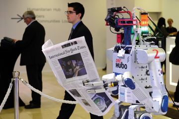 A robot holds a newspaper during a demonstration at the World Economic Forum (WEF) annual meeting in Davos