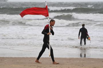Image of man walking on beach holding red flag