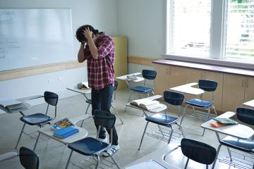 student in classroom with head in hands