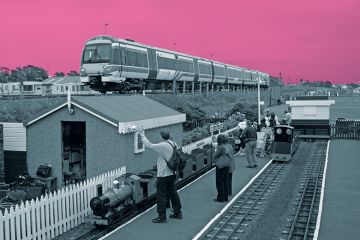 Miniature railway next to real train