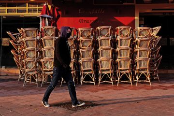 Man with facemask walking past closed cafe during coronavirus pandemic. France.