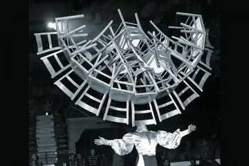 Man balancing lots of chairs