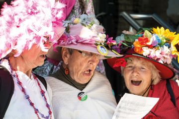 Three women singing from same hymn sheet Three women singing from same hymn sheet