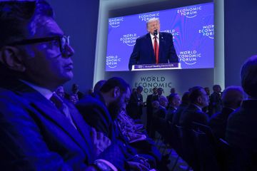 The audience at the World Economic Forum in Davos watch Donald Trump speaking on a big screen