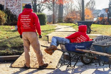 Tulsa USA Nov 15 2017 Construction workers waiting around at residential work site - one is lying in a wheel barrrow or construction cart in winter