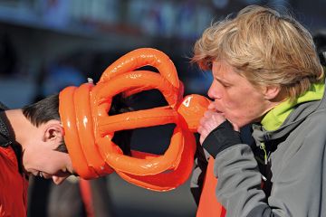 Person blows an inflatable orange crown to illustrate Universal exams can fix  the grade inflation crisis