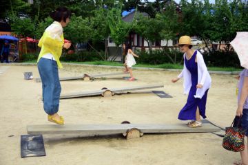 Two women playing on a Korean See Saw,Neolttwigi or nol-ttwigiis a traditional game of Korea typically played by women and girls on traditional holidays such as Korean New Year, Chuseok, and Dano. in the Wolmi Park in Seoul, South Korea