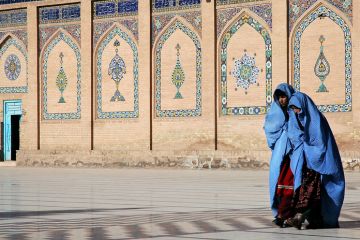 Two women walk in front of the Great Mosque of Herat in Herat, Afghanistan