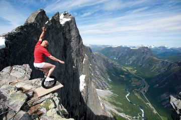 Man riding unicycle at edge of mountain Man riding unicycle at edge of mountain