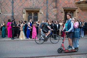 University of Cambridge students going to the Trinity College May Ball, as people ride past on a scooter. To illustrate that elite universities admit fewer local students as intakes grow.