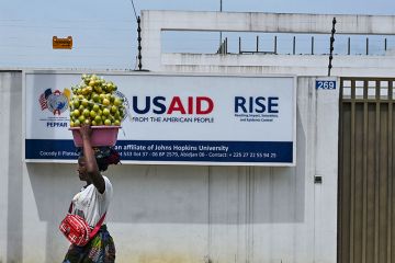 A street vendor walks past the USAID office in Abidjan, Ivory Coast A street vendor walks past the USAID office in Abidjan, Ivory Coast
