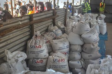 Congolese refugees look through a corrugated metal fence at the final batches of food delivered by the now-dismantled USAID in May 2025 Congolese refugees look through a corrugated metal fence at the final batches of food delivered by the now-dismantled USAID in May 2025