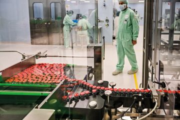 A laboratory technician supervises capped vials during filling and packaging tests of a Covid-19 vaccine candidate, 2020