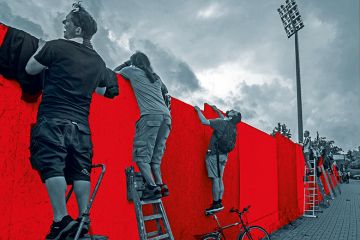 Men trying to look or climb over a wall