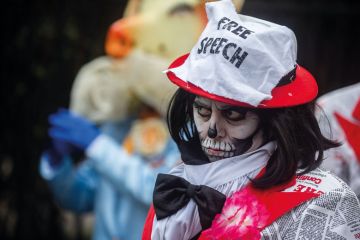 Protester wearing free speech hat in London to illustrate The free speech bill has finally become law - what happens next?