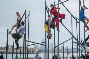 Dance circus production at Canary Wharf of women top of scaffolding and men climbing below