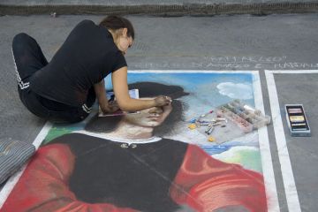 woman draws portrait on pavement with crayons