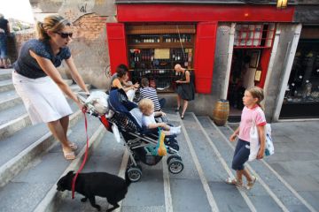 A mother carries a pram up some stairs to illustrate ‘Grant us flexibility’