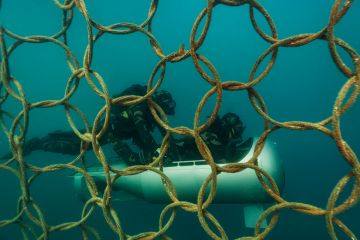 Two divers infant of steel protection under the sea with a submarine as a metaphor of Non-EU scientists face exclusion from sensitive Horizon projects