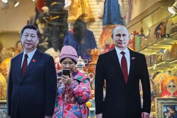 A tourist stands next to cardboard images depicting Chinese President Xi Jinping (L) and his Russian counterpart Vladimir Putin at the touristic Arbat street in downtown Moscow to illustrate Russian research is ‘increasingly isolated’ by Ukraine conflict