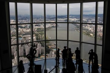 Visitors are silhouetted as they take photographs at the glass-bottomed Seoul Sky observation deck Visitors are silhouetted as they take photographs at the glass-bottomed Seoul Sky observation deck to illustrate UK university explores options in South Korea’s forgotten hub