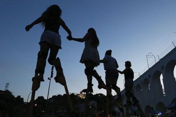People practice walking on stilts during a stilt walking workshop as part of pre-Carnival festivities 