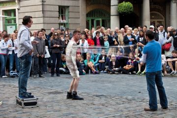 Street Entertainer unwrapping a person wrapped in cling film in Covent Garden, London to illustrate Problem of prestige dogs interdisciplinary campus