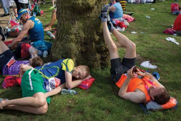 Tired long-distance runners rest after finishing the London Marathon to illustrate people are deep tired