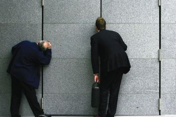 Business men stop to look through the gap in a construction block to illustrate Research council head veto ‘will make vacancies harder to fill’