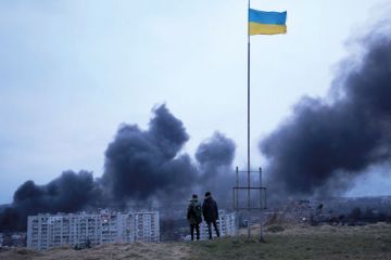 People standing near a Ukrainian national flag watch as dark smoke billows following an air strike in Lviv to illustrate Ukraine universities teach under fire