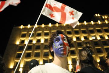 A man with his face painted in the colours of the EU flag and the Georgian flag stands outside the parliament building to illustrate Eastern European scholars stuck between Brussels hope and Kremlin