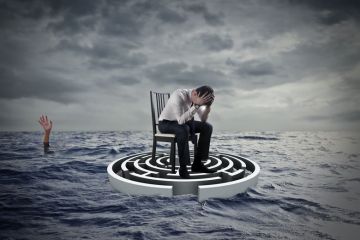 Concept of a person sitting with head in hands on a maze in the sea with a hand in the distance raised to illustrate UK, US law must fix clash between privacy rights and protecting lives