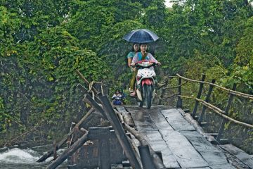 Two people ride on a motorbike across the wooden bridge in the Karen State, Myanmar to illustrate No education ‘better than oppressive one’ for Myanmar students 