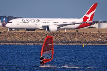 A sail boarder rides in front of a Qantas Airways plane A sail boarder rides in front of a Qantas Airways plane to illustrate New Colombo Plan changes ‘will reverse equity gains’