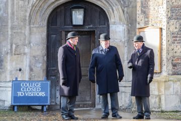 Entrance door shut with a sign reading 'College closed to visitors' at Trinity college at the University of Cambridge, England. Trinity college at the University of Cambridge, England. Men standing at closed door with sign reading 'College to to visitors' to illustrate Elitism cannot be fixed without Oxbridge admissions reform