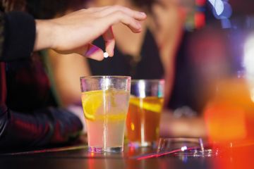 Closeup shot of a hand putting a tablet into a drink  to illustrate Freshers’ Week’s drink spiking  is not only security’s problem