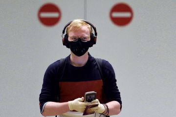 A passenger wearing PPE with two no entry signs behind him.
