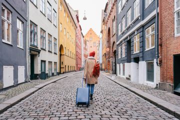 A woman walking down the street pulling a suitcase A woman walking down the street and pulling a suitcase to illustrate wanting to leave