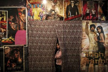 An Indian worker waits for customers as he is surrounded by Bollywood film posters at a small cinema in New Delhi An Indian worker waits for customers as he is surrounded by Bollywood film posters at a small cinema in New Delhi to illustrate India’s JNU target for Bollywood film and ‘jingoistic nationalism’