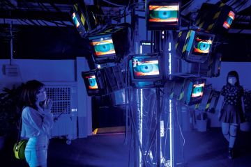 Visitors are seen at an exhibition called 'Heart of Cyberpunk' as it displays human eyes on TV screens