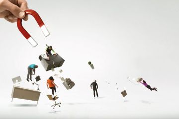 Giant hand and magnet picking up office and workers to illustrate labour pains