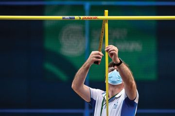 The high jump bar height is adjusted and measured by an official to illustrate English universities await clarity on impact of GCSE entry bar