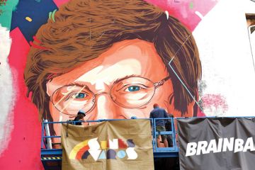 A painter makes finishing touches on a mural showing a portrait of Katalin Kariko as she is mentioned in the story