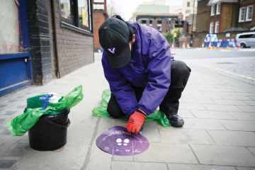 Person removes social distancing sticker as a metaphor for returning to university as will be able to reopen