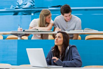 Students sitting in lecture with girl thinking at laptop