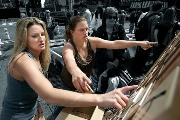 Two ladies pointing at a giant Sudoku in the street as a metaphor for problem solving.