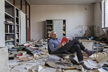 Montage of a person sitting reading in an Abandoned office with many papers on the floor Montage of a person sitting reading in an Abandoned office with many papers on the floor