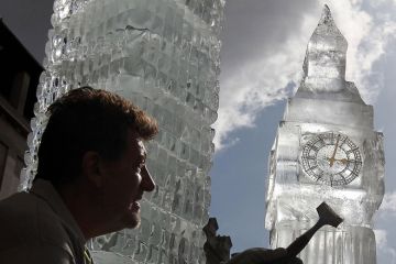 British ice sculptor Duncan Hamilton with his sculpture of London's iconic Big Ben to illustrate No Westminster government will raise fee cap, universities warned